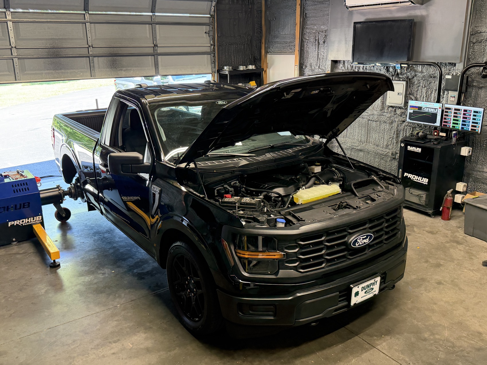 A Ford F-150 with the hood up, strapped to the dyno at the shop